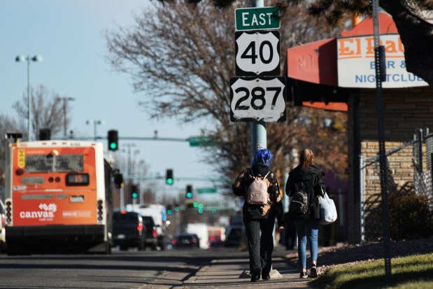 Pedestrians walk near East 40 and 287 signs on East Colfax Ave. in Denver on Tuesday, Dec. 5, 2023. (Photo by Hyoung Chang/The Denver Post)