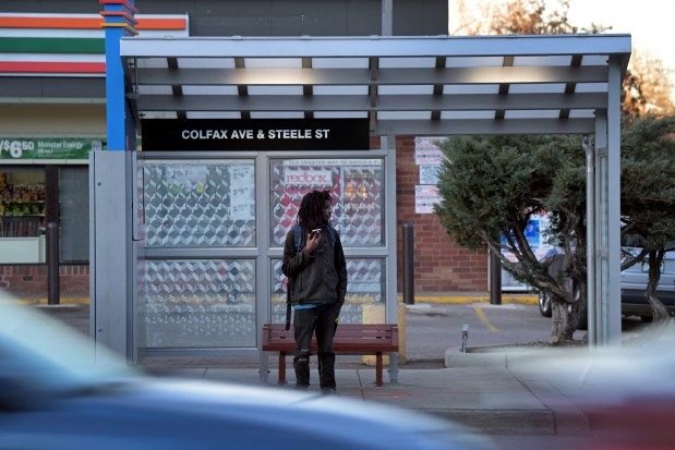 A passenger waits for a bus at Colfax Ave. and Steele St. in Denver on Tuesday, Dec. 5, 2023. (Photo by Hyoung Chang/The Denver Post)