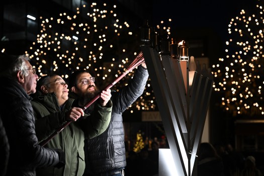 From left, Dr. Ben Machanic, Alan Hoffman and Rabbi Shmuly Engel light the candles on the large Menorah outside of the Chabad of Cherry Creek
