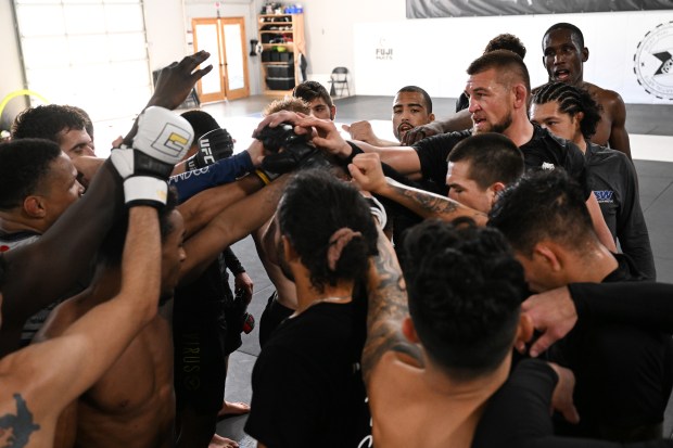 Dustin Jacoby, right, and other fighters put their hands together at the end of a daily training session at Factory X on December 6, 2023 in Englewood, Colorado. (Photo by Helen H. Richardson/The Denver Post)"