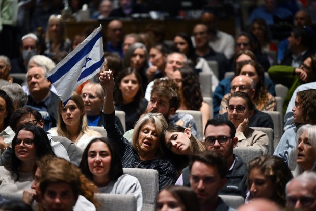 Teena Slatkin holds an Israeli flag as she and her daughter Cassie, right, join in singing a song during a prayer vigil