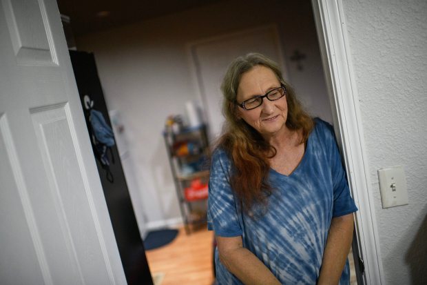 Cara Conrad, 59, leans against a doorway in her apartment in Houston on Oct. 12, 2023. Conrad, who was formerly homeless, moved into her own apartment through Houston's homeless response system. (Photo by Mark Felix/Special to The Denver Post)